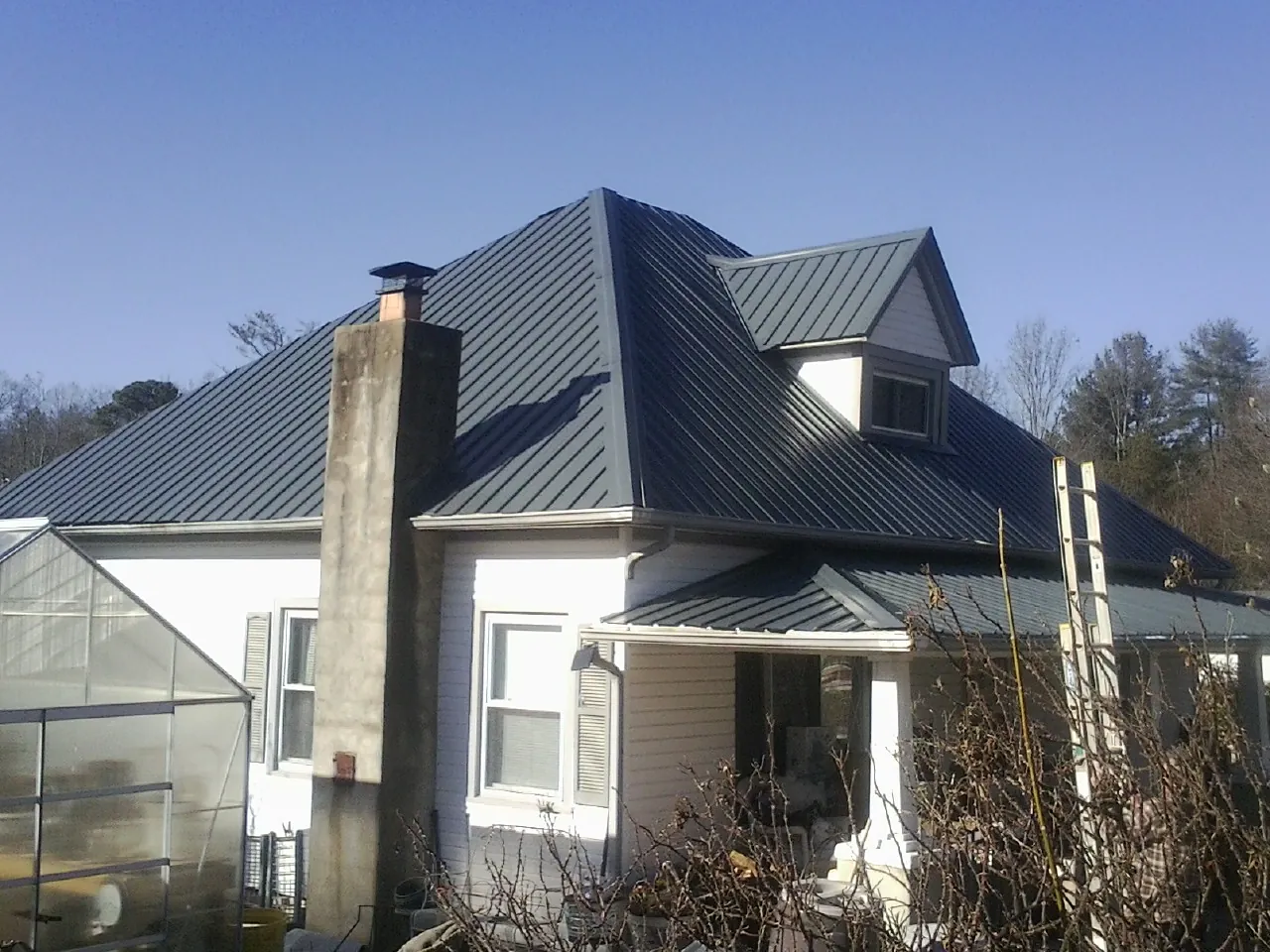 Dark blue standing seam metal roof on a white farmhouse with dormer — Slate & Tile Roof Repair by Roofing Brothers in New Washington
