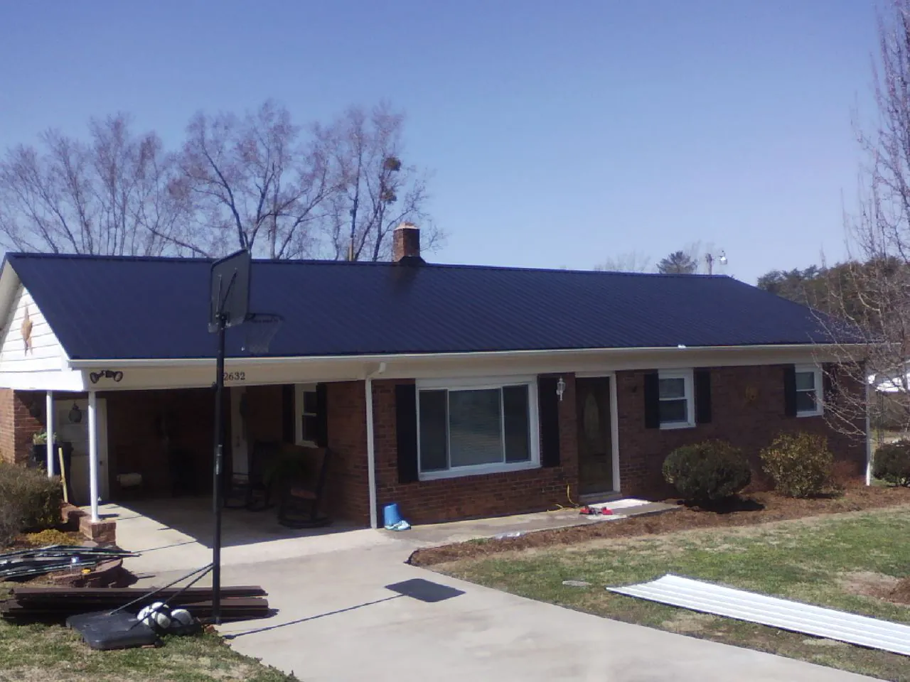 Finished dark blue metal roof on a brick ranch with a carport in New Washington
