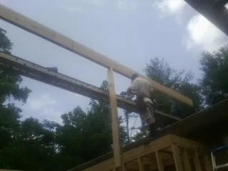Carpenter setting a ridge beam over a new addition frame — Ice Dam Removal by Roofing Brothers in New Washington