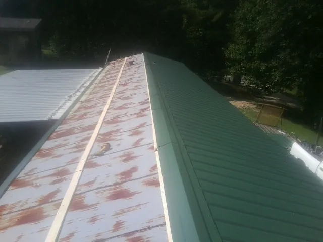 Old rusted panels beside newly installed green metal roofing — Wind Damage Roof Repair by Roofing Brothers in New Washington