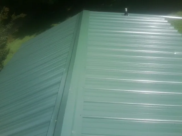 New green metal panels meeting at the ridge of a roof — Flat Roof Repair work by our crew in New Washington