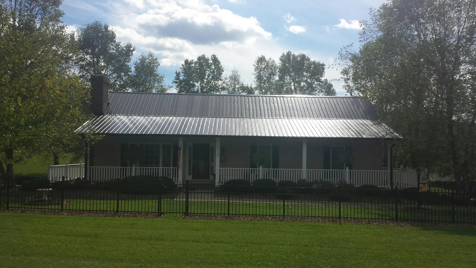 Gray metal roof on a brick ranch with a full width front porch — Gutter Guard Installation work by our crew in New Washington