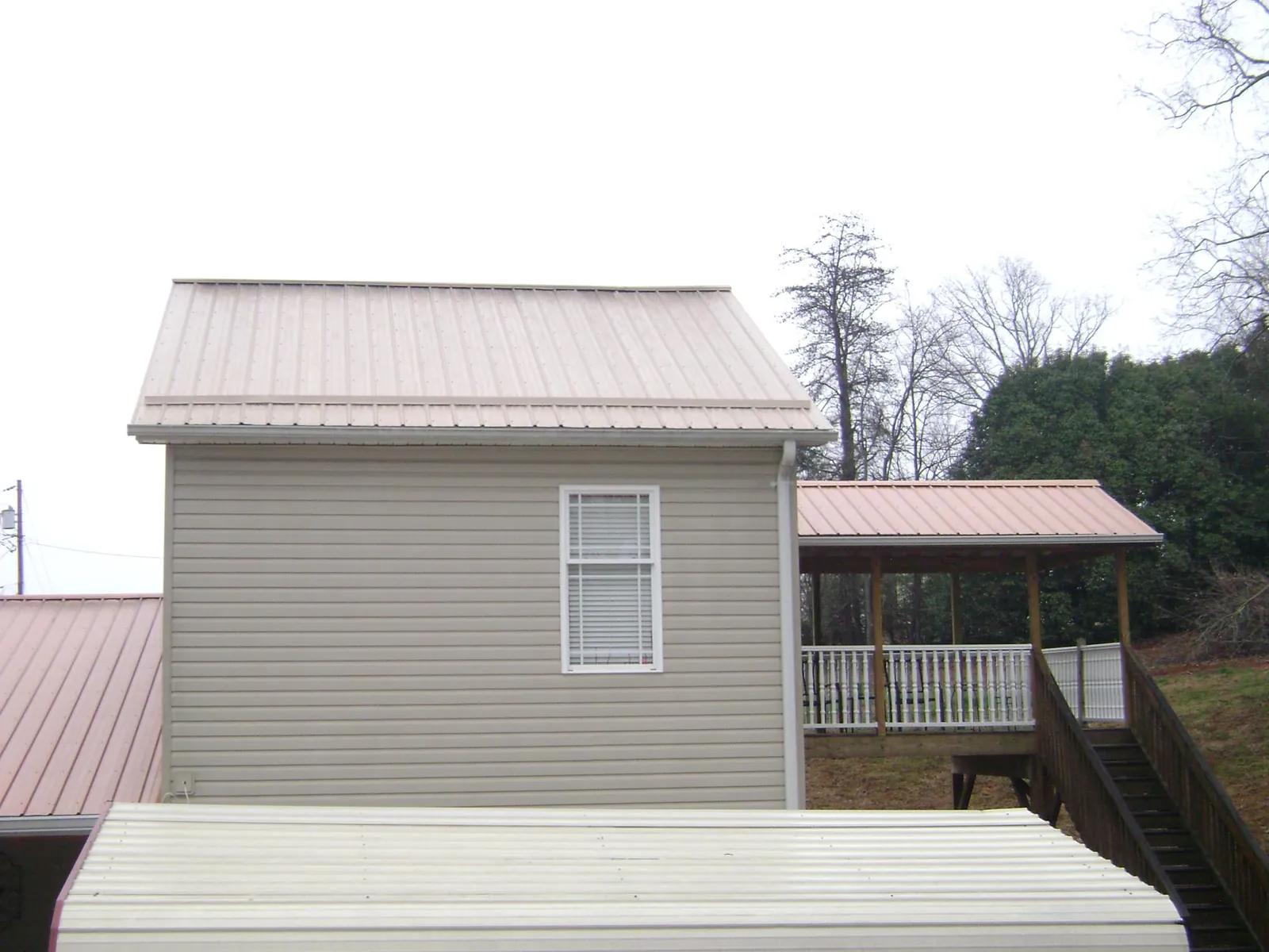 Tan metal roofs on a two story addition and attached porch, from a Roof Replacement job in New Washington