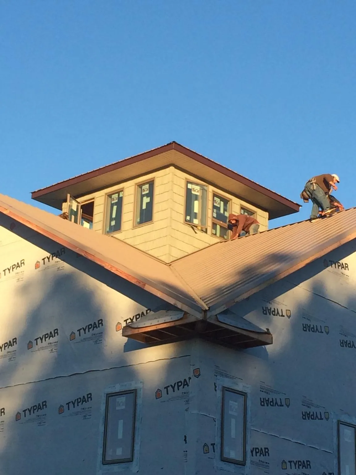 Roofers working around a rooftop cupola on a new metal roof at sunset — Roof Waterproofing in New Washington by Roofing Brothers